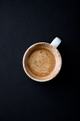 Cup of coffee on black background. Top view. Copy space