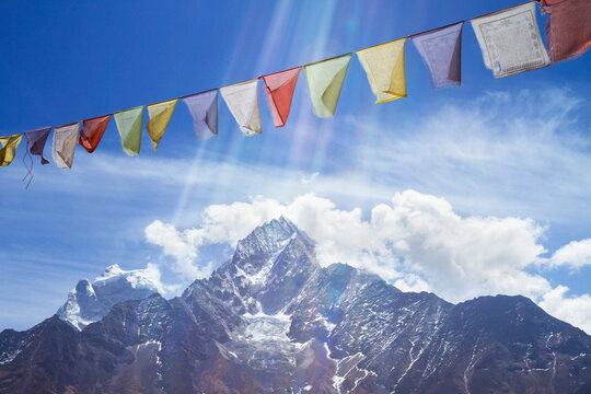 Prayer flags hanging over snow covered Mt. Everest against cloudy sky