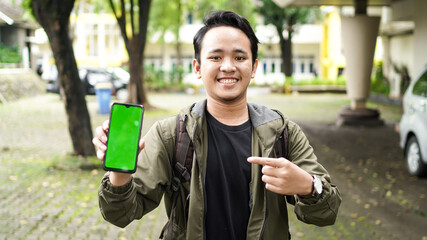 Asian man pointed at the green screen cell phone with a smile