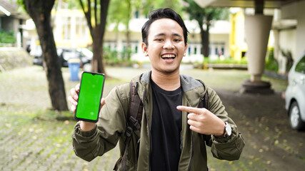 Asian man pointed at the green screen cell phone with a smile