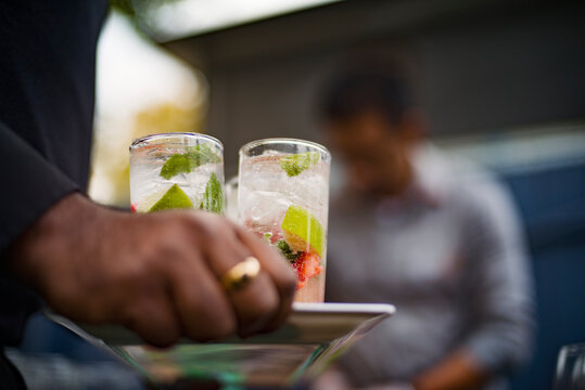 Cropped image of waiter holding refreshing drinks in tray at outdoor restaurant