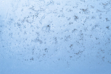 Obraz premium frozen glass in the cold, icy blue pattern in winter on the window. the texture of the ice and snowflakes