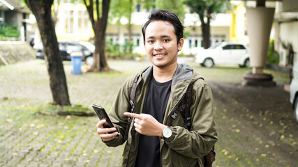 Asian man wearing a bag pointing the phone