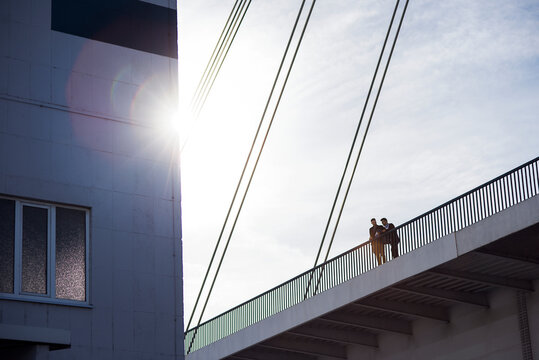 Low angle view of men standing on bridge by building against clear sky