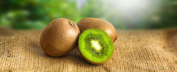 Kiwi slice placed on wooden table with light from the window with blur kiwi plant.