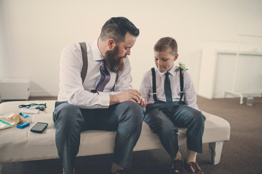 Bridegroom showing wedding ring to pageboy while sitting on bed at home
