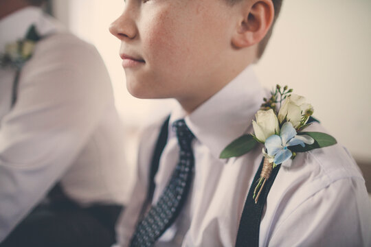 Close-up of pageboy with flowers on suspender sitting by bridegroom at home