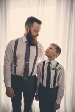 Bridegroom and pageboy looking at each other while standing against curtain