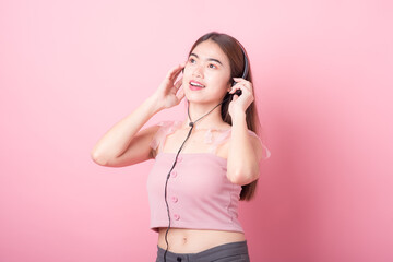 Happy smiling young asia woman with headphones enjoying listens to music over pink background