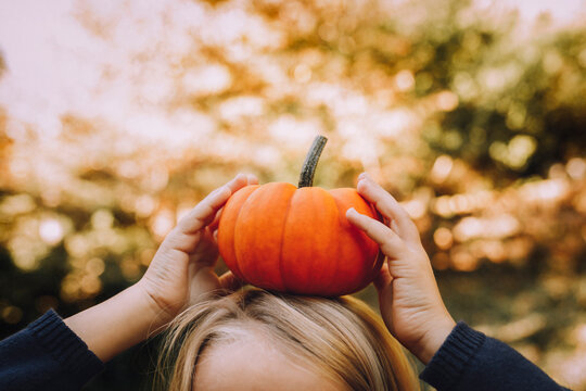 Cropped image of girl balancing pumpkin on head