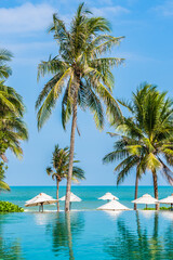 Umbrella and chair around outdoor swimming pool with coconut palm tree