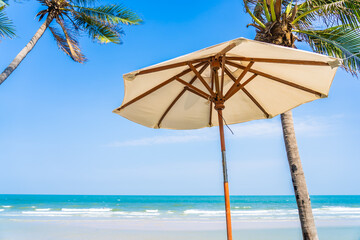 Umbrella and chair around sea beach ocean with coconut palm tree