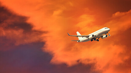 Fototapeta na wymiar Zoom photo of passenger airplane taking off at sunset with beautiful orange sky and clouds