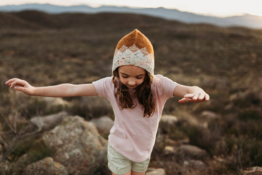 Girl with arms outstretched walking on field