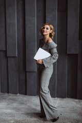 beautiful smart cute charming attractive elegant business woman in a stylish gray suit with a laptop in her hands. Soft selective focus.