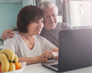 Elderly couple looking at computer in the kitchen