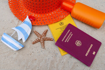 Reisepass mit Impfausweis Sonnenhut und Sonnenlotion am Strand