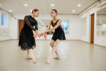 Fototapeta premium Teacher rehearsing with young ballerina in class