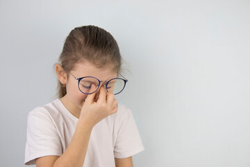 little girl wipes tired eyes from glasses, cute child feeling discomfort and fatigue,tired after long wearing spectacles,eyesight problem,isolated on white background,eye fatigue