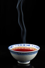 Top view of blue china tea cup, steaming, black background, vertical, with copy space