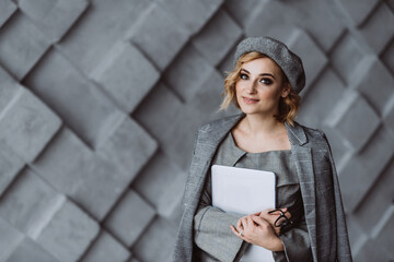 beautiful smart cute charming attractive elegant business woman in a stylish gray suit with a laptop in her hands. Soft selective focus.