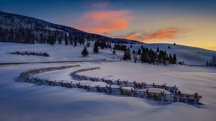 snowy landscape with snow barriers after sunset