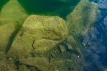 The waters of the basalt lake, the stones in the lake are covered with algae, clear and pure water.