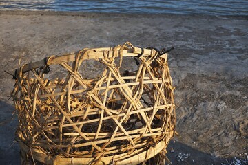 Rustic handwoven bamboo basket on a sandy beach with surf visible at the top