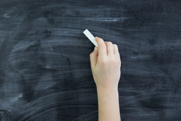 hand with chalk on the background of a blackboard in white chalk.