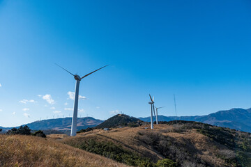 再生エネルギーのイメージ　青空の下回転する風車　風力発電プラント