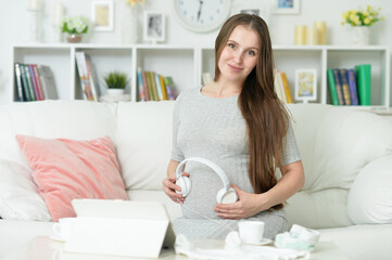 Fototapeta na wymiar happy pregnant woman with headphones on belly