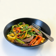 Mexican beef fajitos in a black plate on a white background