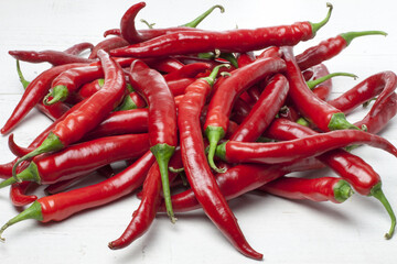 Red and ripe hot chillies arranged on a white table. Such peppers are perfect for spicy Asian or Mexican dishes, but not only.