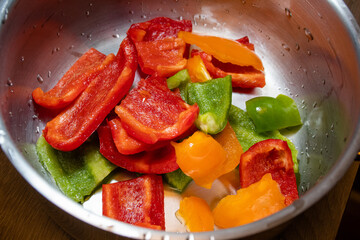 Pieces of red, green and orange bell peppers in a silver cooking pot