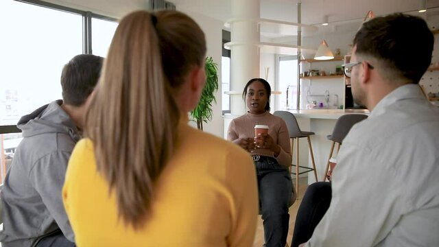 Diverse group of people sitting in circle in group therapy session.