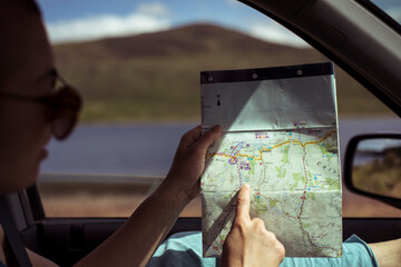 person on road trip in car points at old map