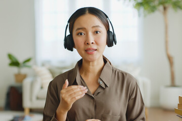 POV Young Asian woman wearing headphone talking on video call conference or virtual meeting on...