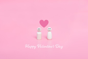 Valentine's day. Couples of wooden doll and hearts shape in pink background.