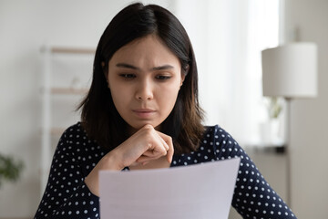 Worried young asian woman sit at desk read official bank notification about debt penalty fee...