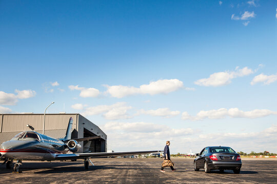 Man walking towards car while disembarking from airplane against cloudy sky