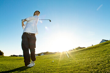 Man taking a shot of golf while standing against clear sky