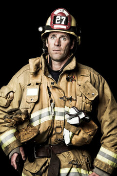 Portrait of firefighter standing against black background