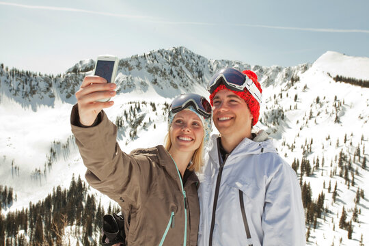 Couple taking selfie while standing on snow covered mountain