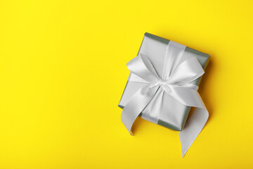 Trendy attractive minimalistic gray gift on the yellow background. Colors of 2021. Merry Christmas, St. Valentine's Day, Happy Birthday and other holidays concept.