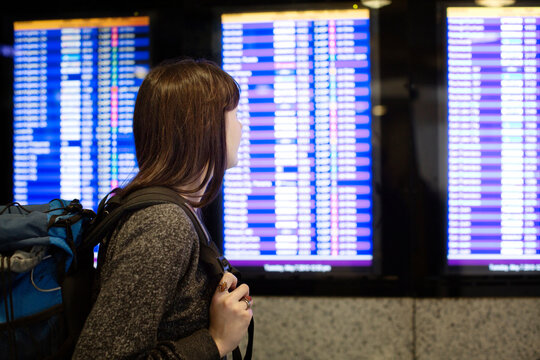Side view of woman looking at arrival departure board
