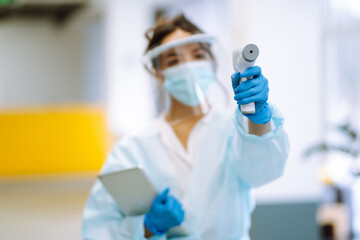 Disease control expert with an Infrared thermometer equipment to check the temperature at office during pandemic in quarantine. COVID-19.