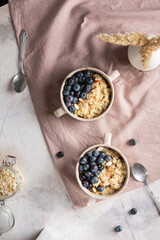 Flat lay of bowls with oatmeal porridge and blueberries