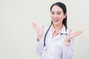 Beautiful young Asian woman doctor smiling cheerfully showing gestures in a medical gown