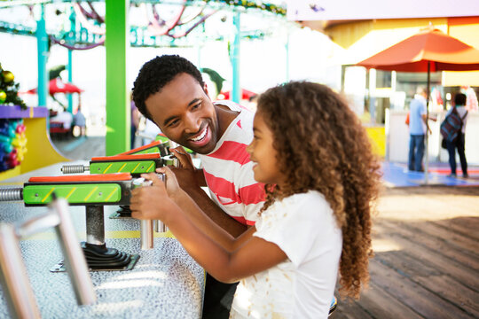 Father looking girl while playing with squirt gun in amusement park