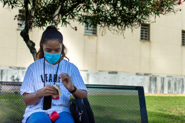 girl cleaning her glasses at the university with a mask